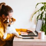 How Pets Are Reshaping Employee Benefits a woman working on a laptop while holding her puppy in her lap