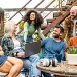 Why Sustainable Business Policies Will Attract and Retain Gen Z group of young diverse students sitting together in a room filled with plants.